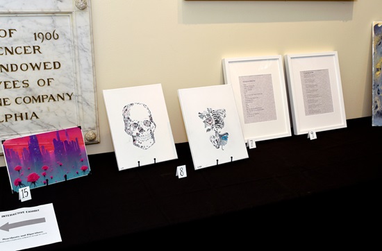 Six pieces of art, from paintings to poetry, displayed on a table at the Pennsylvania Hospital art show
